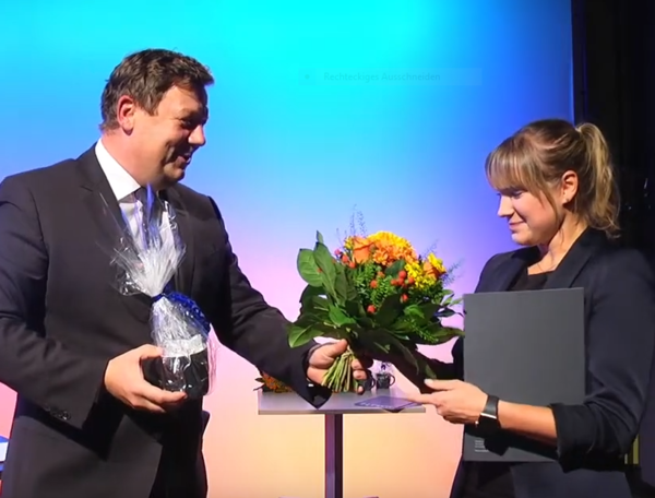 Die Preise des HTWK-Fördervereins 2019 wurden pandemiebedingt während einer (fast ausschließlich) virtuellen Veranstaltung verliehen. Prof. Markus Krabbes übergibt den Preis an Marie-Louise Heinich. (Foto: HTWK Leipzig) Mann übergibt Frau einen Blumenstrauß und beglückwünscht sie